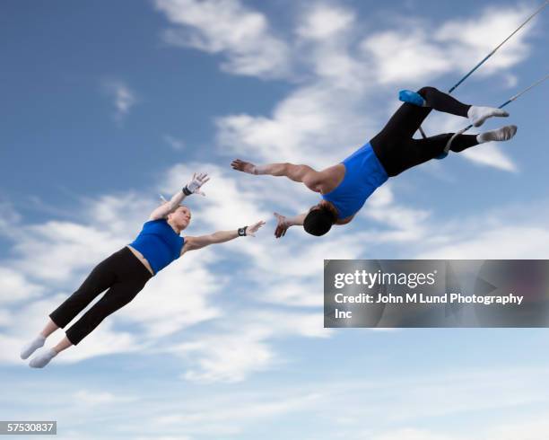 acrobats catching each other in the air - trapez stock-fotos und bilder