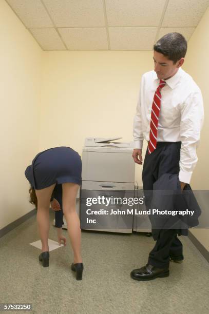 businessman admiring female colleague?s buttocks as she bends over - bending over in skirt stock-fotos und bilder