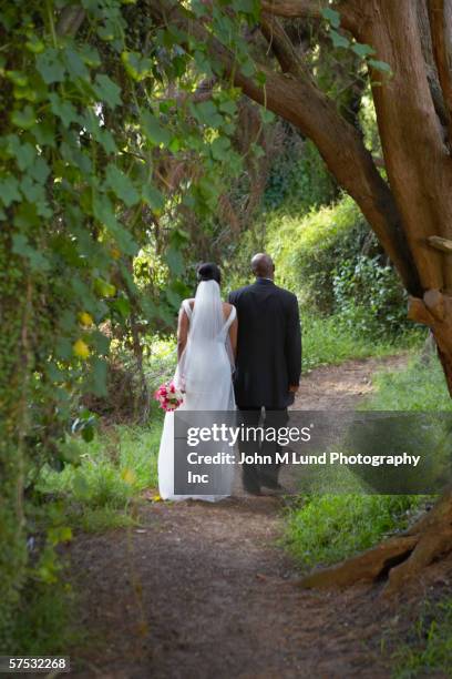 newlyweds walking along dirt path - bride walking stock pictures, royalty-free photos & images