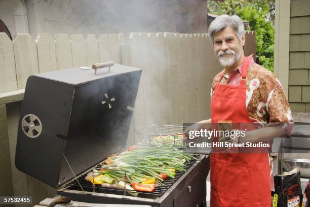 middle-aged man grilling vegetables - grilled vegetables stock pictures, royalty-free photos & images