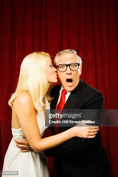 young woman kissing a shocked older man - old man young woman stock pictures, royalty-free photos & images