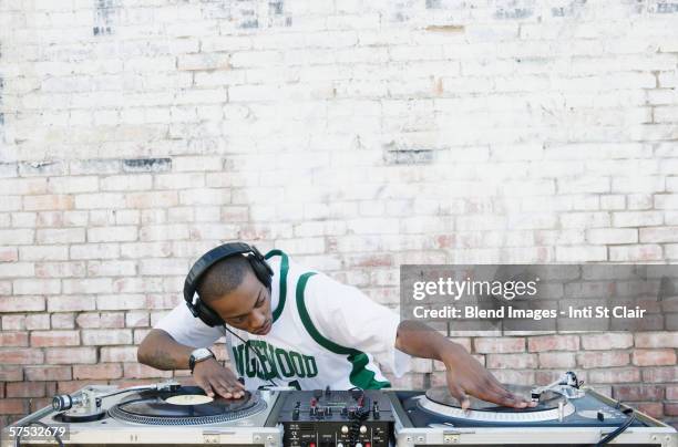 teenage boy using turntables and headphones - dj de club fotografías e imágenes de stock