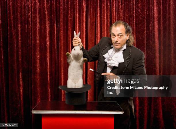 magician pulling a rabbit out of a hat - magician stockfoto's en -beelden