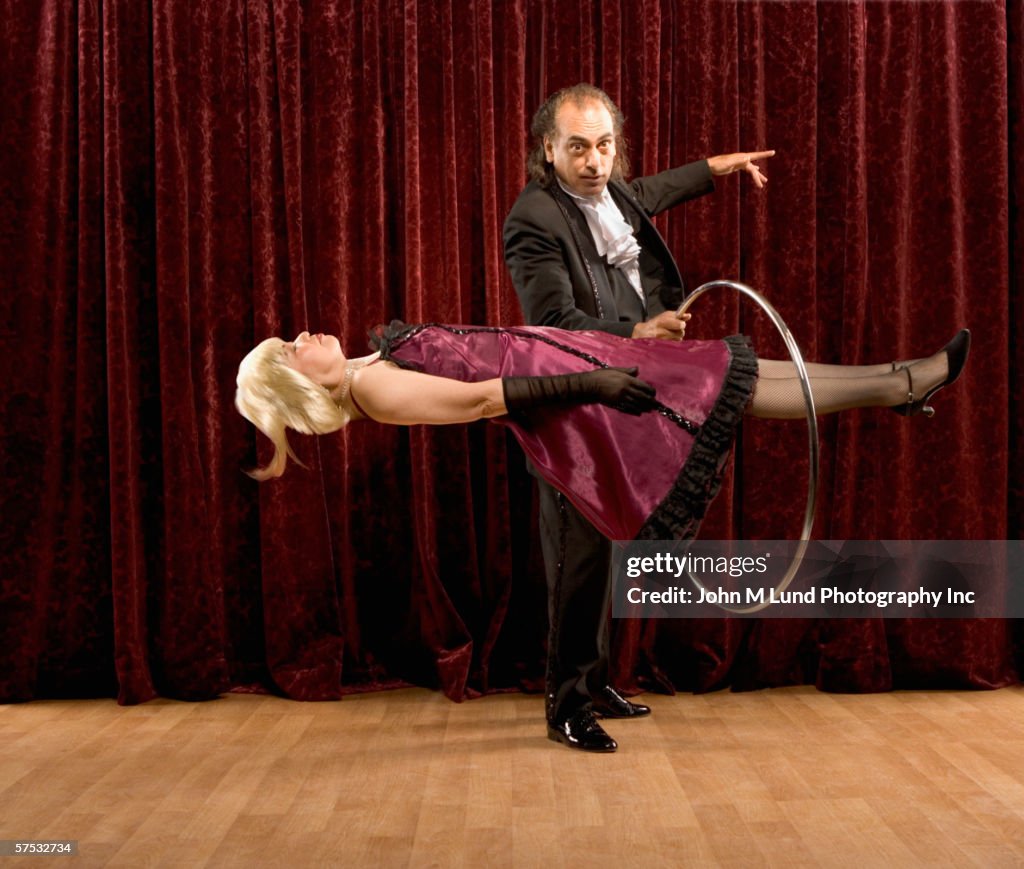 Magician putting ring around levitating woman