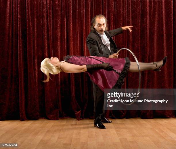 magician putting ring around levitating woman - magician stock pictures, royalty-free photos & images