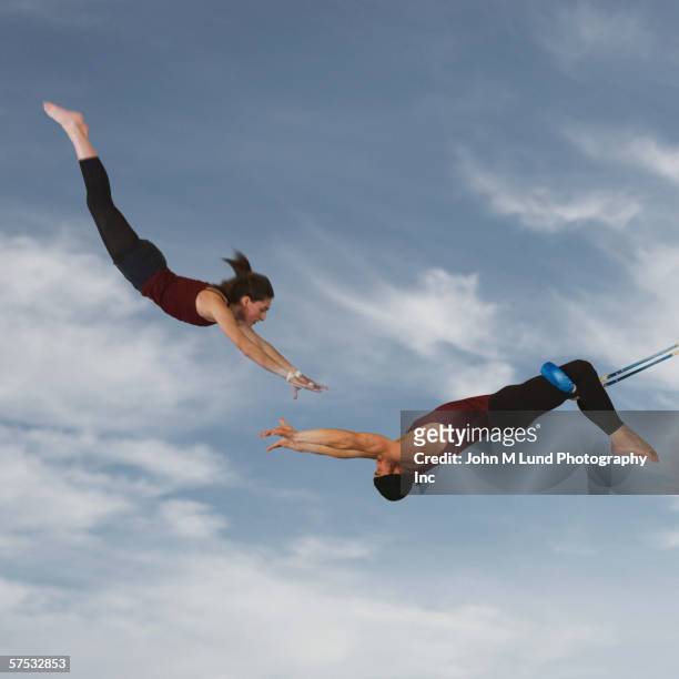 acrobats catching each other in the air - match sport stockfoto's en -beelden