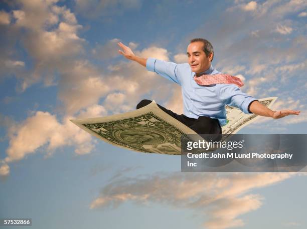 businessman flying on a dollar bill - 空飛ぶ絨毯 ストックフォトと画像