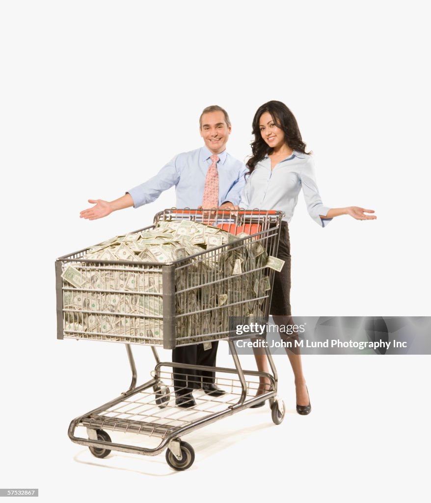 Businesspeople pushing shopping cart full of money