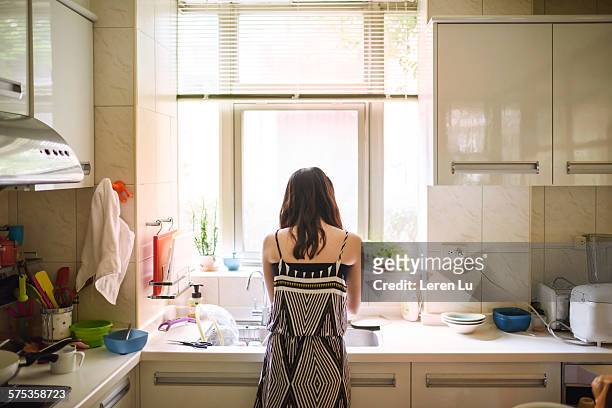 teenage girl washing dishes in kitchen - afwas doen stockfoto's en -beelden