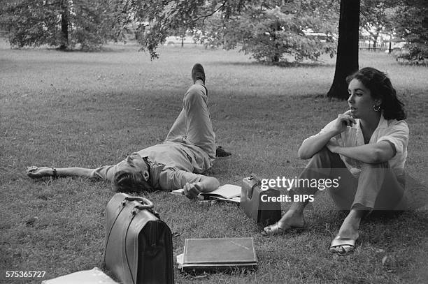 Actors Montgomery Clift and Elizabeth Taylor lounging on the grass during the filming of 'Raintree County' in Indiana, 1956.