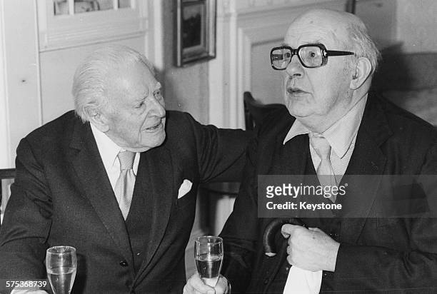 English writer Ben Travers celebrating his 94th birthday by drinking champagne with his friend, and fellow writer, Sir John Betjeman, during a lunch...