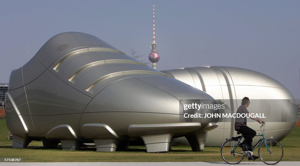 A man cycles past a giant sculpture feat