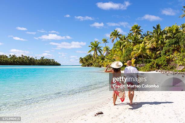 tourist couple hand in hand walking on beach - アイツタキ ストックフォトと画像