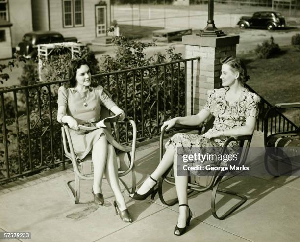 two young women sitting on terrace, talking, (b&w) - two women talking stockfoto's en -beelden