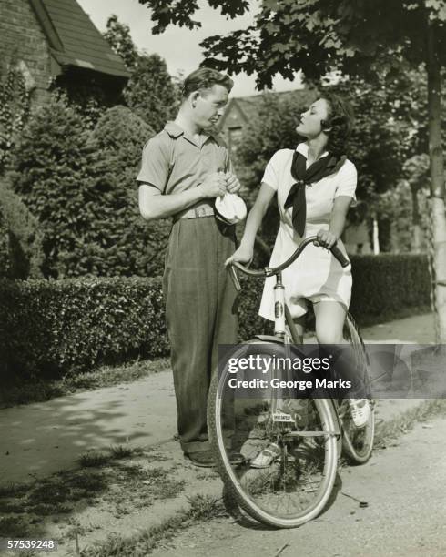 jeune couple parler sur la rue, femme sur un vélo (b & w - 1930 photos et images de collection