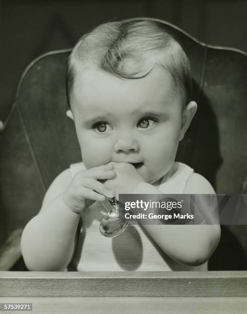 baby (6-9 months) sitting in high chair, holding spoon, (b&w), portrait - 1940's stock pictures, royalty-free photos & images