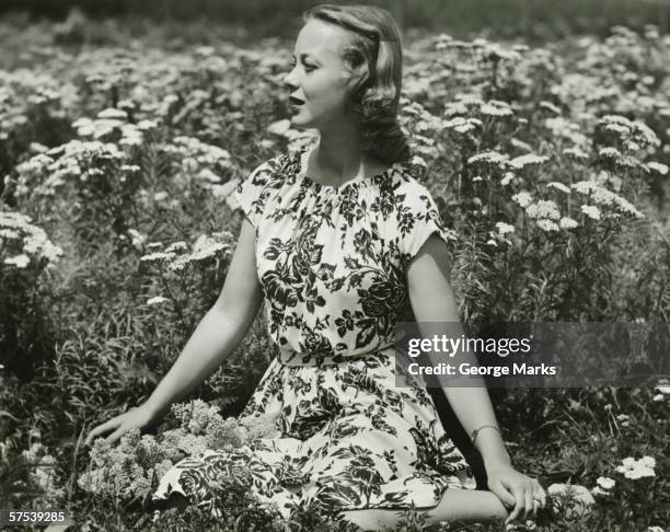 woman in flowery dress sitting in meadow among flowers, (b&w), portrait - floral pattern dress stock pictures, royalty-free photos & images