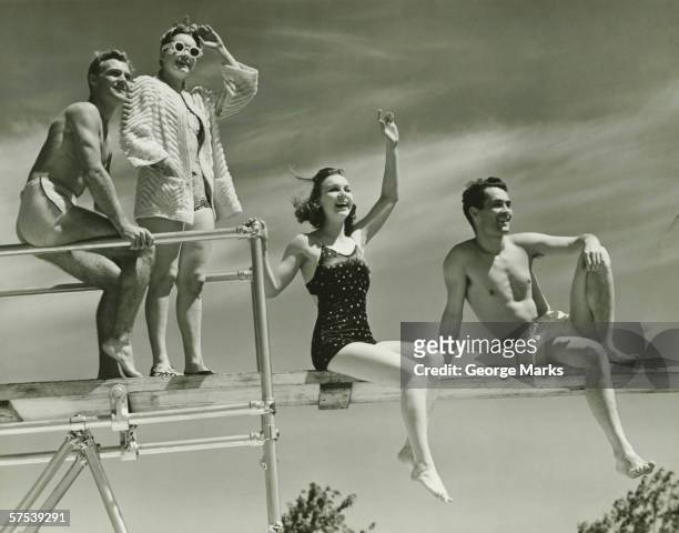 two couples on springboard, (b&w), low angle view - ouderwets stockfoto's en -beelden