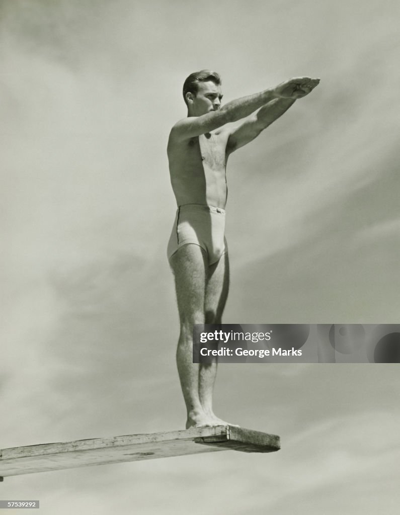 Man on springboard ready to jump, (B&W), low angle view