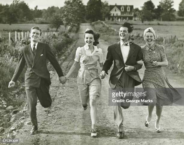 two couples holding hands, running on footpath, (b&w) - old fashioned stock pictures, royalty-free photos & images