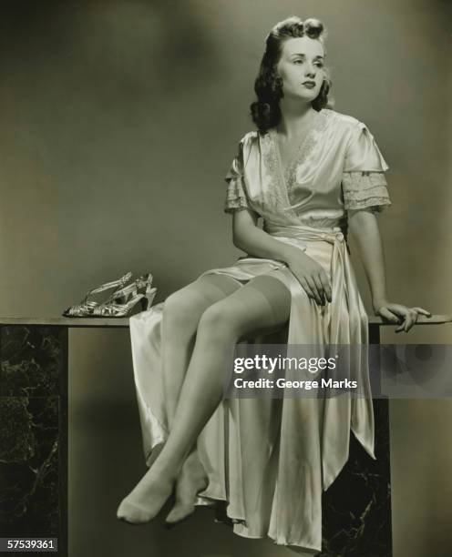 young woman in elegant dressing gown sitting in studio, (b&w) - long nylon legs stock pictures, royalty-free photos & images