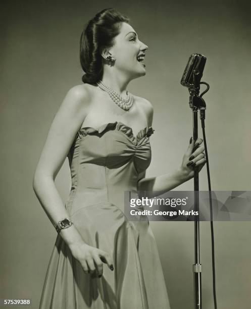 young woman at microphone, singing, (b&w) - vintage microphone stock pictures, royalty-free photos & images