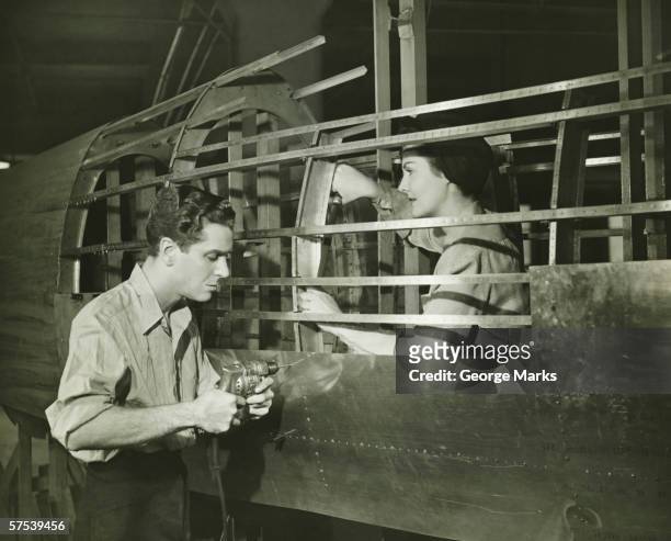 young man and woman working in plane body in factory, (b&w) - world war ii stock pictures, royalty-free photos & images