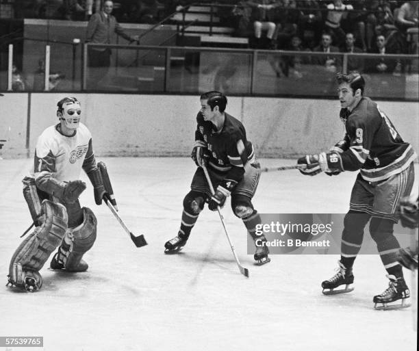 Canadian professional hockey player Roger Crozier , goalie for the Detroit Red Wings, defends the net against the advances of the two New York...