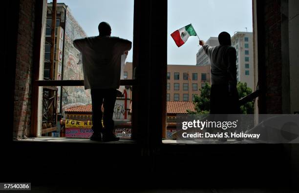 Two men stand in the windows of a construction site as hundreds of thousands of immigrants demonstrate on May 1, 2006 in downtown Los Angeles,...