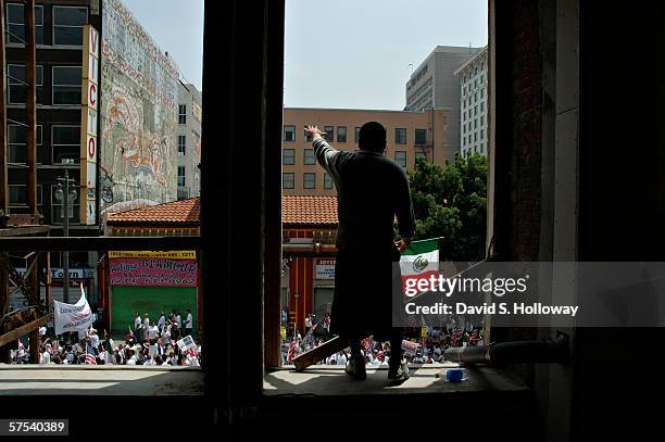 Man waves a mexican flag from a building as hundreds of thousands of immigrants demonstrate on May 1, 2006 in downtown Los Angeles, California. The...