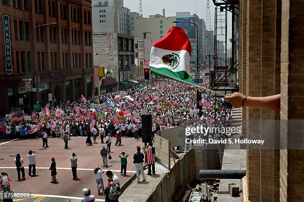 Man waves a mexican flag from a building as hundreds of thousands of immigrants demonstrate on May 1, 2006 in downtown Los Angeles, California. The...