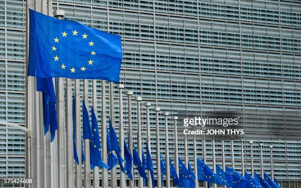 This photo taken on July 15, 2016 shows European Union flags flying at half-mast in front of the European Commission building in Brussels on July 15...