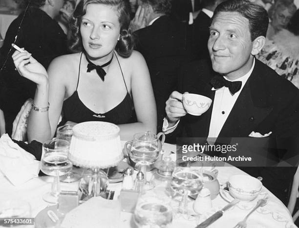 Actors Rose Stradner and Spencer Tracy sitting at a dinner table together during a black-tie event, circa 1945.