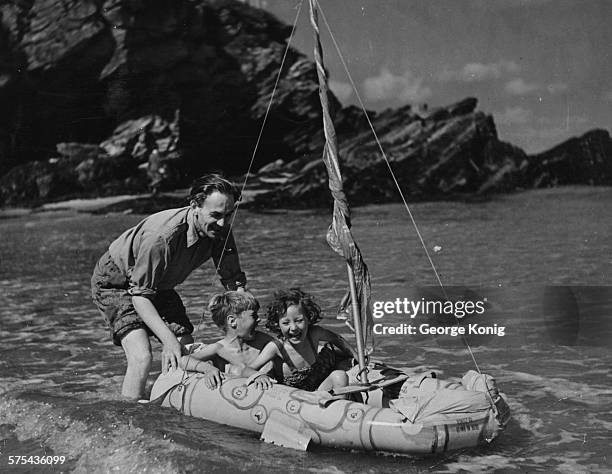 Airman Nigel Tangye, husband of actress Ann Todd, pictured pushing their children David and Francesca in a rubber dinghy, in the sea on the coast of...