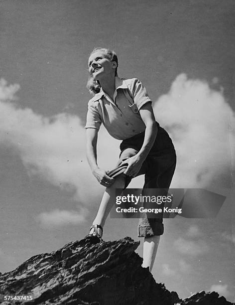 Portrait of actress Ann Todd rolling up her trousers as she walks along a rock outcrop during a holiday in Cornwall, England, circa 1949.
