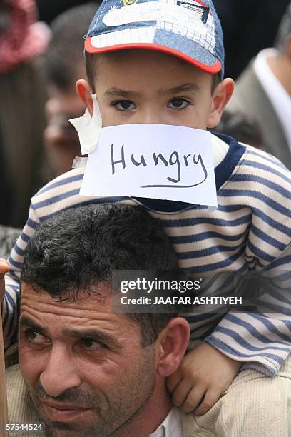 Palestinian man carries his son on his shoulders during a protest by some 1,000 people over the Palestinian Authority's failure to pay government...