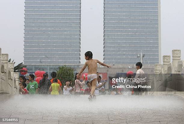 Child plays on a fountain at the "Bayi" Square on May 6, 2006 in Nanchang of Jiangxi Province, China. Hot and rainy weather has hit regions of South...