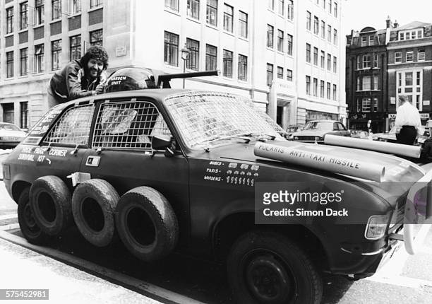 Radio disc jockey Dave Lee Travis demonstrating his 'London Proof Car', an Austin Allegro with wire covered windows and a machine gun turret, outside...