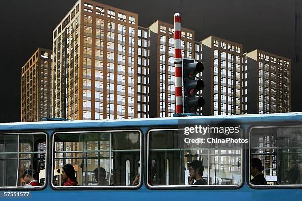 Passengers ride a bus past a giant real estate billboard on May 2, 2006 in Nanjing of Jiangsu Province, China. Housing prices in 70 large and medium...