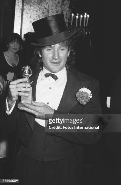 American comedian and actor Robin Williams, dressed in a three-piece tuxedo and a top hat, displays his Golden Globe trophy backstage at the Beverly...
