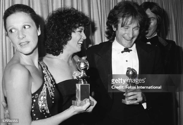 Backstage at the Golden Globes Awards, American actress Linda Lavin holds an award trophy and looks to her right at as actress Joyce Dewitt...
