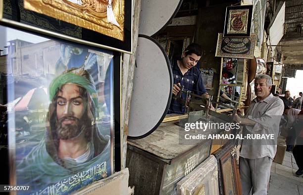 An image of Shiite Imam Abbas, son of Imam Ali, adorns the side of a shop as an Iraqi craftsman assembles a frame, in Baghdad, 09 May 2006. Iraq's...