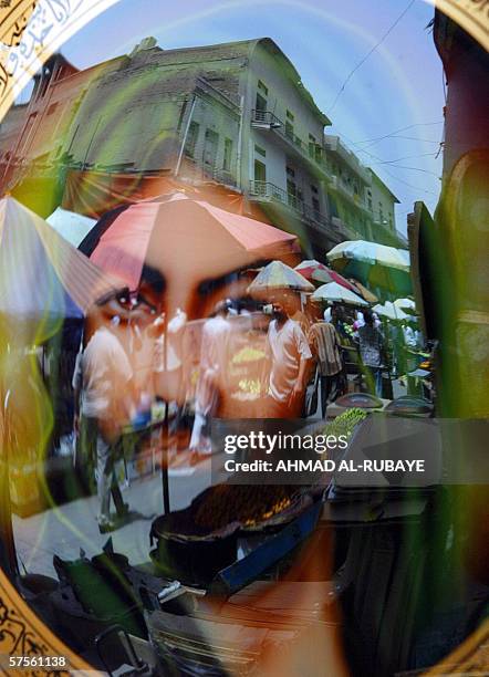 Baghdad market is reflected on an image of Shiite revered Imam Hussein as it hangs at the entrance to a shop, 09 May 2006. Iraq's Prime...
