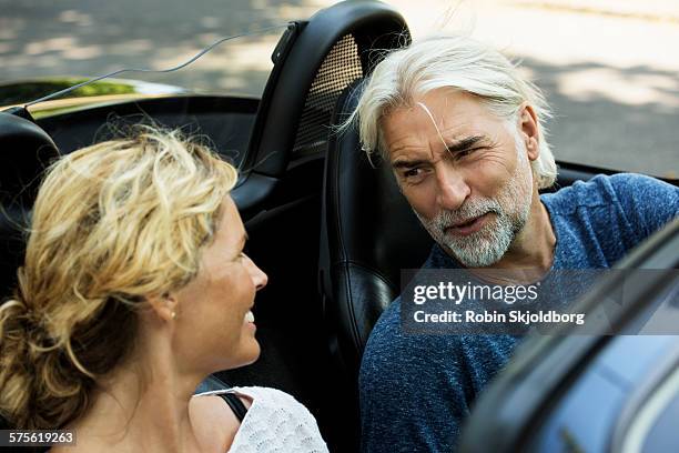 man and woman talking in open car - convertible stockfoto's en -beelden