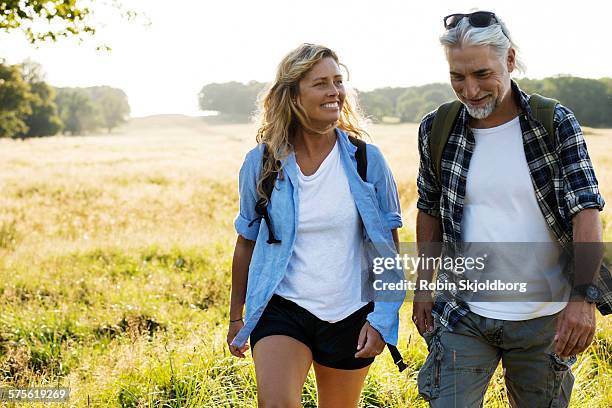 smiling mature man and woman hiking - 40s couple sunny stock pictures, royalty-free photos & images