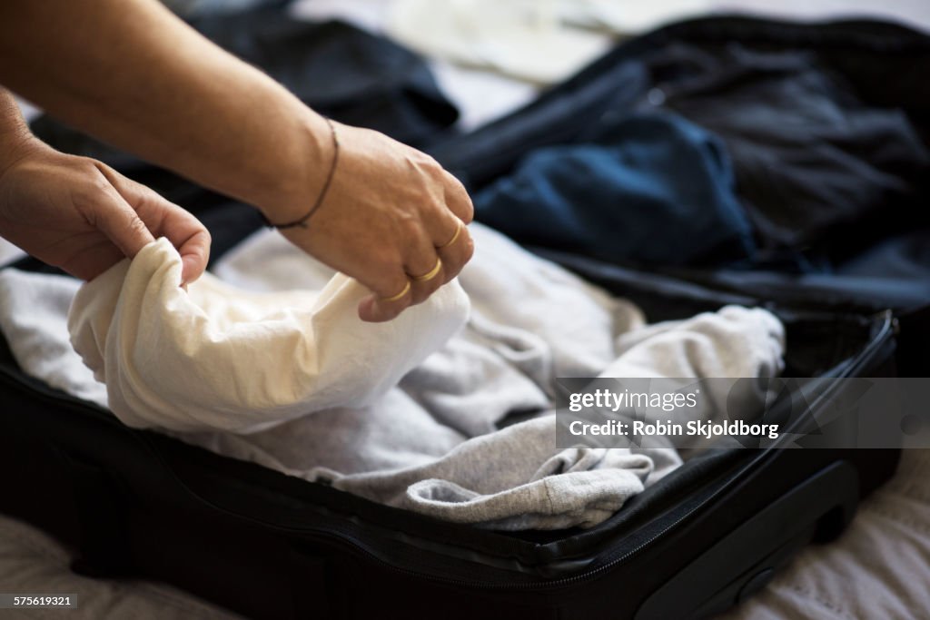 Closeup of Womans hands packing suitcase