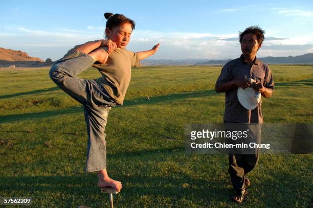 Bolor doing her daily practice while her father watches in a field on July 7, 2005 in Khovd, Mongolia.