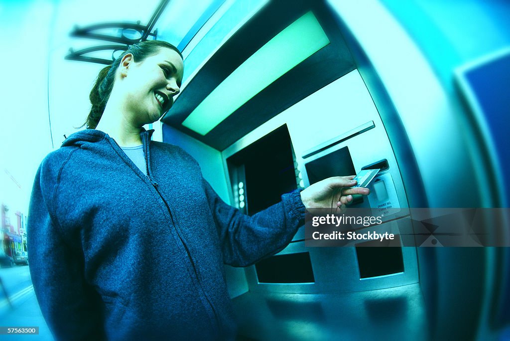 Low angle view of a young women at an automatic cash machine