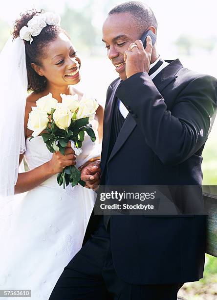 side profile of a bride with the groom talking on a mobile phone - black veil brides stock pictures, royalty-free photos & images