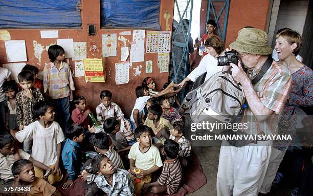 AFPLifestyle-India-society-children-tourism" Tourists take photographs of street children at a medical camp at the railway station in New Delhi, 09...